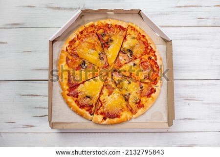Pizza in a cardboard box. white wood background. Food concept. View from above.