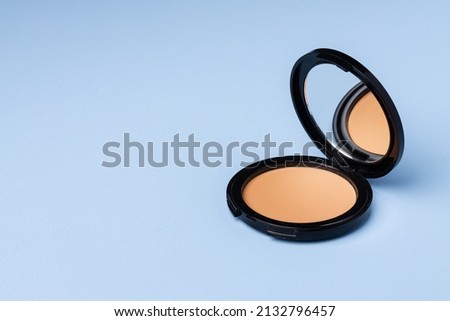 Compact face powder on blue background front view Royalty-Free Stock Photo #2132796457