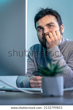 Tired bearded man looks at the computer screen.
