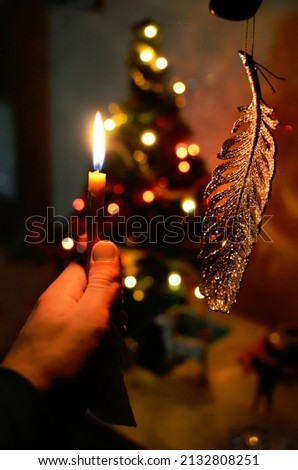 Candle on the background of blurry Christmas tree lights. Front view.