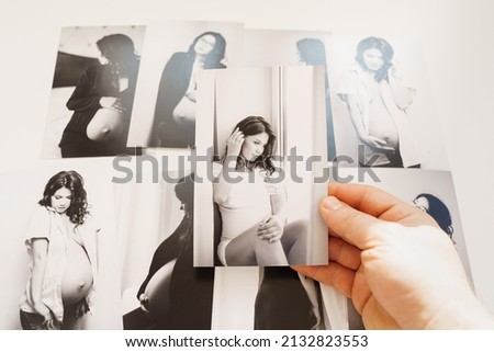 Men's hands hold pictures of a beautiful pregnant woman. photo shoot with a professional photographer. photo studio or printing services.