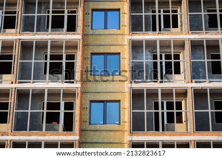 Insulation of the building with mineral wool outside. Protection of the house from the cold, noise insulation of the residential townhouse. Construction of an apartment building. High quality photo