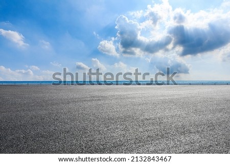 Empty asphalt road near the lake under blue sky