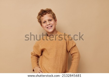 Photo of young boy in a beige sweater posing fun Lifestyle unaltered