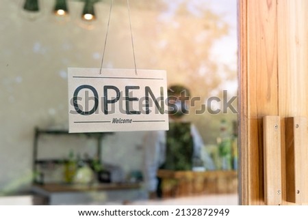 Business owner turned a sign to reopen a cafe after quarantine during the coronavirus pandemic. Man holding a sign write open. Small community business, restaurant owner, billboard for opening a shop