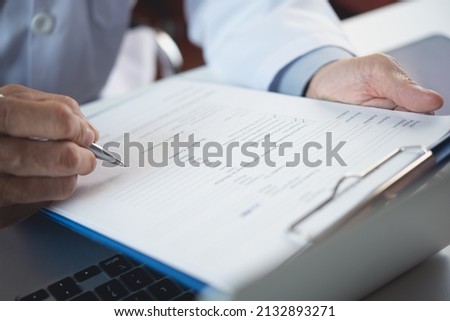 Close up of male doctor filling medical chart, checklist document, patient's information on clipboard. Doctor writing, signing on health insurance document in hospital, healthcare and medicine concept Royalty-Free Stock Photo #2132893271