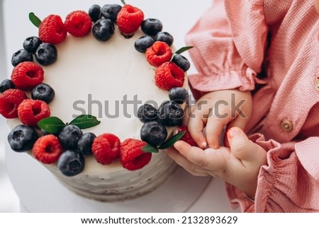 birthday cake with berries. Raspberry and blueberry.Children's hands