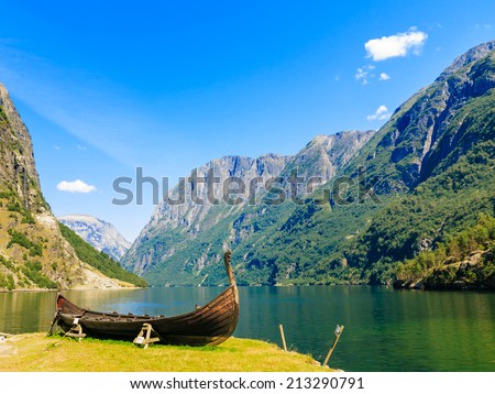 Tourism and travel. Mountains and fjord Sognefjord in Norway, Scandinavia. Old viking boat on seashore. Royalty-Free Stock Photo #213290791