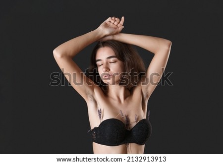 Unshaven armpit concept. Girl is holding lavender flowers in front her armpits. Symbol of unshaven body parts. Body positivity and naturalness. Problems home depilation on black background
