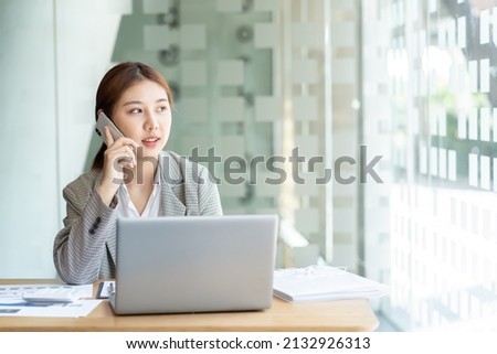 Closeup image of a beautiful asian woman holding and using mobile phone in office, business financial and investment concpet.
