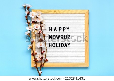 Sprigs of the apricot tree with flowers on blue background Text Happy Nowruz Holiday Concept of spring came Top view Flat lay Hello march, april, may, persian new year Greeting card
