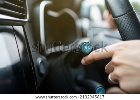 Unrecognizable woman driver activating the adaptive cruise control or steering assistant on the control stick behind steering wheel in electric vehicle - EV car. Driving Assist system in modern car. Royalty-Free Stock Photo #2132945617