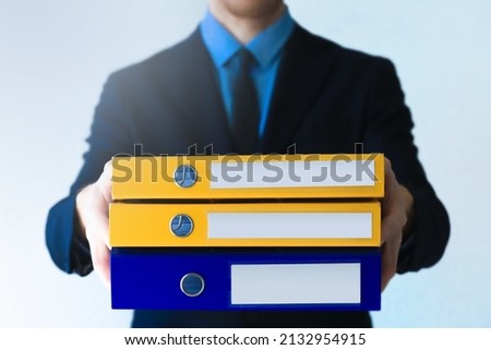 Office man in suit and tie in with stack of ring binders for archiving documents over clean background. File, Ring Binder, Emotional Stress. Royalty-Free Stock Photo #2132954915