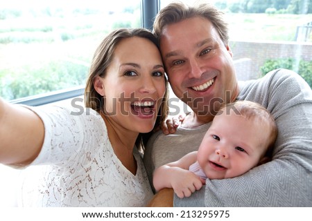 Close up portrait of a happy couple taking a selfie with baby