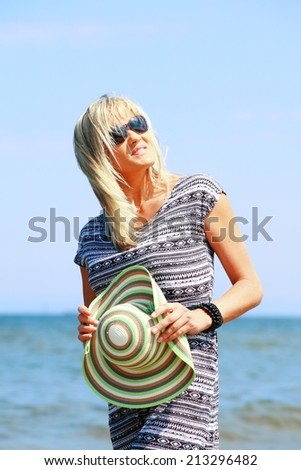 mature woman with hat on beach enjoying summer holiday