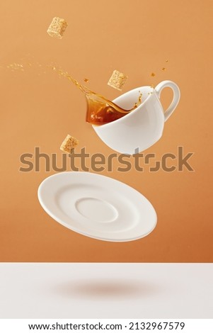 Coffee Spilled From A White Cup. 
Coffee splashing out of cup with flying sugar cubes. Royalty-Free Stock Photo #2132967579