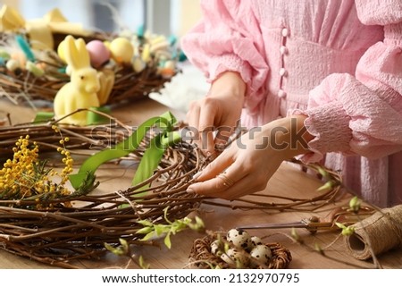 Woman making beautiful Easter wreath on wooden table, closeup Royalty-Free Stock Photo #2132970795