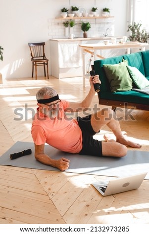 Senior man doing fitness exercises with virtual class and holding dumbbells - wellbeing and wellness concept