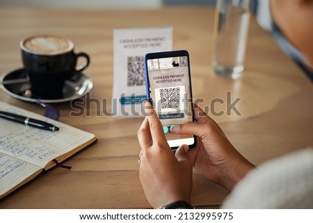 Close up of hands of young woman scanning qr code for cashless payment at cafeteria. Detail of customer hand making payment through smartphone and scan code at cafe. African woman paying with QR code. Royalty-Free Stock Photo #2132995975