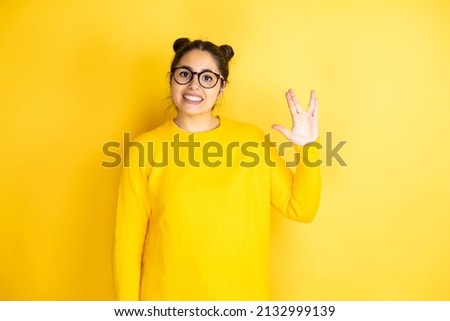 Young beautiful woman wearing casual sweater over isolated yellow background doing hand symbol
