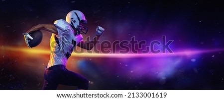 Dynamic portrait of male american football player in sports equipment at stadium in motion on dark background with mixed neon light. Collage, poster. Flyer for ad, design. 3D render. Royalty-Free Stock Photo #2133001619