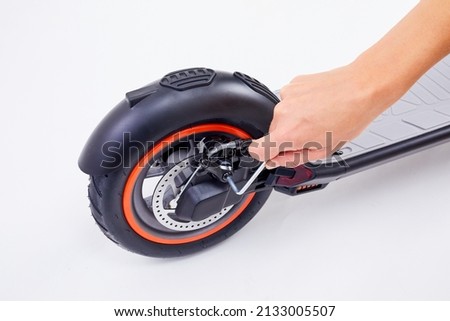 Hand repairing electrical scooter on white background. Repair service for fixing electrical escooters. Technological concept. Royalty-Free Stock Photo #2133005507