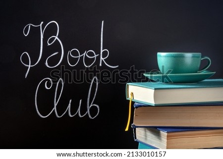 Book Club Concept. A stack of hardcover books with chalk lettering on a blackboard with a cup of coffee Royalty-Free Stock Photo #2133010157