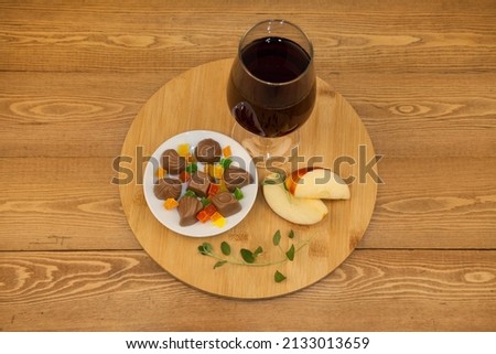 A glass of red wine. Chocolates. Red sliced apple. valentine's day. on a white saucer. the concept of new year and Christmas. on a white background. The concept of love. A glass cup.Still-life.