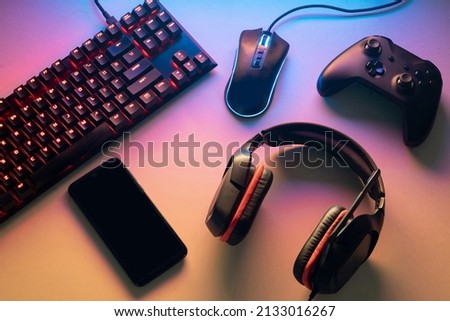 Gamer work space concept. gaming set up. top view of a gaming gear, keyboard, mouse, gamepad, joystick, headset and a smartphone on a colorful desk