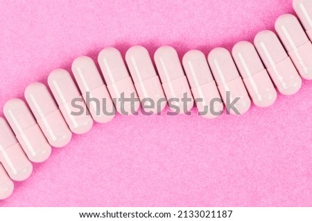 The Pink capsule pills on pink background with copy space.