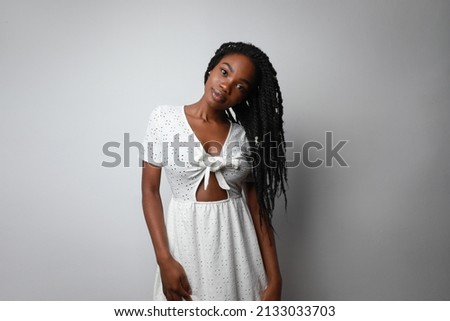 Portrait of young African woman with long braids posing over white wall. 