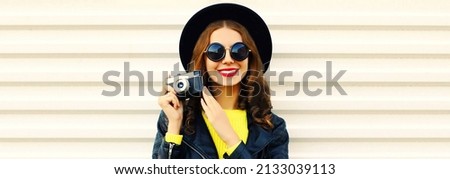 Portrait of happy smiling young woman photographer with film camera on white background
