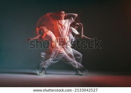 Dancing young sporty girl moving in fiery hip-hop dance in red neon studio light. Long exposure. Breakdancing school ad Royalty-Free Stock Photo #2133042527
