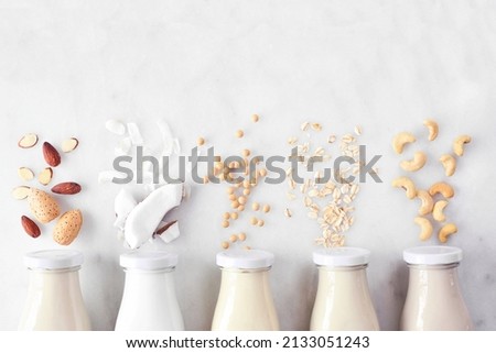 Vegan, plant based, non dairy milk. Variety in milk bottles with ingredients. Above view over a white marble background. Royalty-Free Stock Photo #2133051243