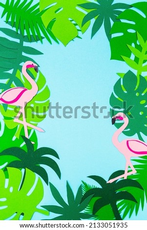 Tropical paper background. Colorful leaves of monstera, palms and flamingos on a blue background. Copy space, flat lay.