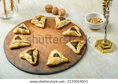 Gomentashi cookies traditional for the Jewish holiday of Purim on a wooden board next to the menorah and wheat ears. horizontal photo