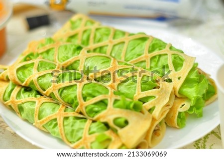 Openwork pancakes with lettuce and stuffing rolled into tubes, soft focus. Delicious picnic recipe Royalty-Free Stock Photo #2133069069