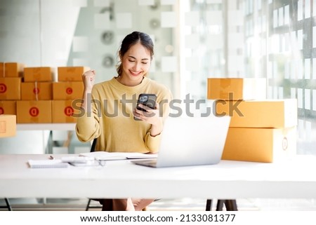 Startup SME small business entrepreneur of freelance Asian woman using a laptop with box Cheerful success Asian woman her hand lifts up online marketing packaging box and delivery SME idea concept Royalty-Free Stock Photo #2133081377