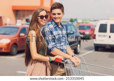 portrait of young couple with shopping cart outdoors