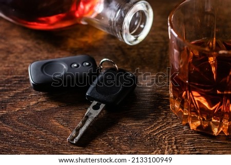 Alcoholic drink in a glass and car keys on a wooden desk. Drunk driving concept Royalty-Free Stock Photo #2133100949