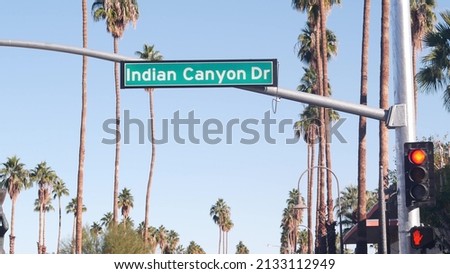 Palm trees and blue sky, Palm Springs resort city near Los Angeles, street road sign, semaphore traffic lights on crossroad. California desert valley summer road trip on car, travel USA. Indian Canyon