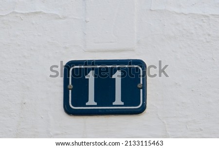 PLAQUE WITH NUMBER 11 ON WHITE WALL