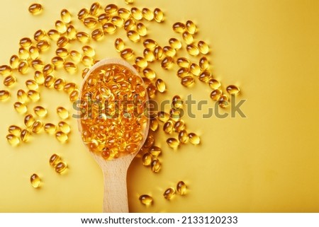 Vitamin D3 in a wooden spoon on a bright yellow background is the concept of health care and immunity support.
