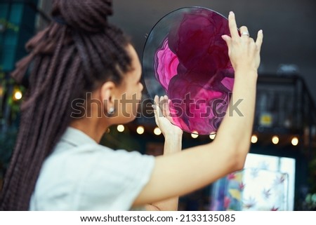 Painter looking at a circular fluid art painting in her hands