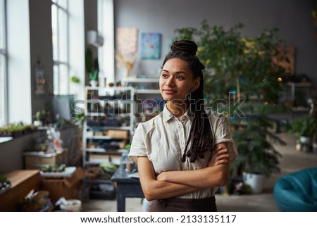Smiling dreamy floral decorator with her arms folded looking away Royalty-Free Stock Photo #2133135117
