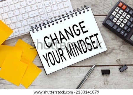 open notepad on wooden background near yellow stickers and white keyboard. text in notepad. Change your mindset