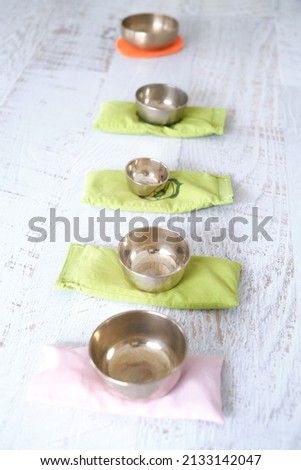 Small singing bowls on white wooden surface for meditation or massage, zen bowls on peds