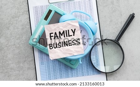 Family Business. Family business written in a white notepad near a pen, a calculator, magnifying glass, usa money on a wooden background. Business concept.