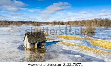 Aerial view to the partly frozen water covered floodplain with the old traditional hay barn in t the front Royalty-Free Stock Photo #2133170771