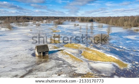 Aerial view to the partly frozen water covered floodplain with the old traditional hay barn in t the front Royalty-Free Stock Photo #2133170773